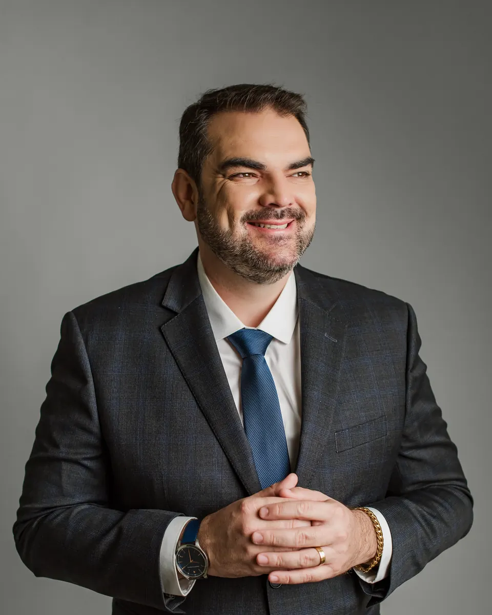 Retrato de Denisson Rabelo Rebonato, de terno e gravata azul, sorrindo